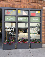 Storefront with colorful window display and flowers on a city street