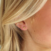 Close-up of a person wearing gold earrings with blonde hair.