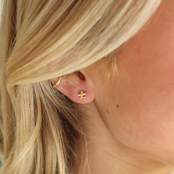 Close-up of a person wearing gold earrings with blonde hair.