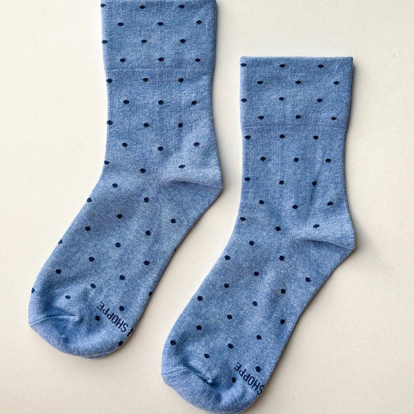 Pair of blue socks with black dots on a beige background