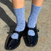 Person wearing black shoes and blue polka dot socks on a concrete surface