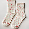 White socks with red polka dots on a light gray background
