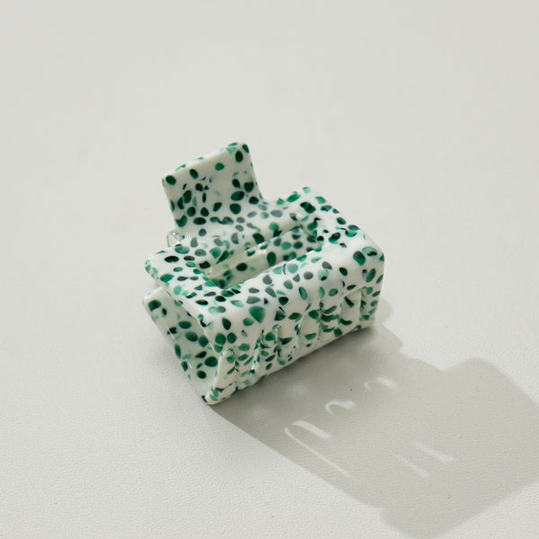 Green and white speckled mini square hair claw on white background.