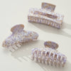 Set of three light purple and gold swirled hair clips on a white background