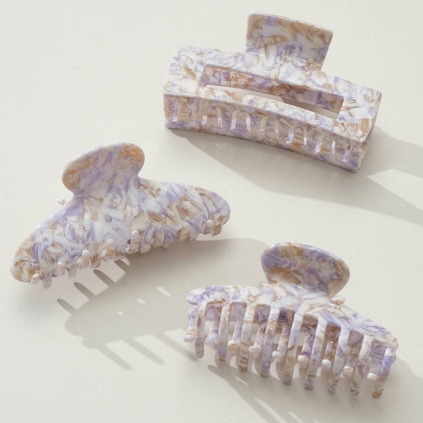 Set of three light purple and gold swirled hair clips on a white background