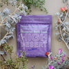 Purple package of High Desert Mineral Bath Soak surrounded by desert plants on a beige background