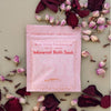 Desert Rose mineral bath soak packet surrounded by rose petals and petals on a light background