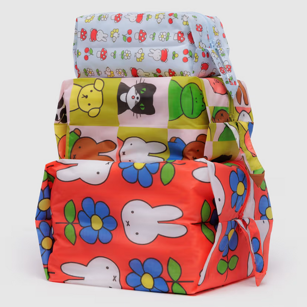 A stack of three expandable nylon packing cubes featuring colorful designs with the Miffy character.