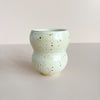 Speckled off-white ceramic cup on a light gray background