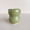 Green ceramic cup with speckled texture on a light gray background