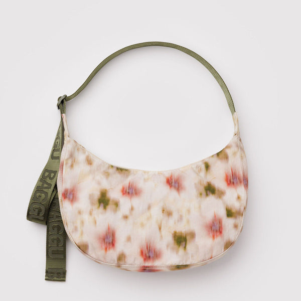 Abstract cream, red, and green floral nylon crescent bag with a green strap against a white background.