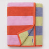 Colorful striped towel with a brand label folded on a light gray background