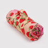 Rolled-up picnic blanket with strawberry pattern  with a carrying strap on a light gray background