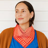 Woman wearing a red patterned scarf with a white background