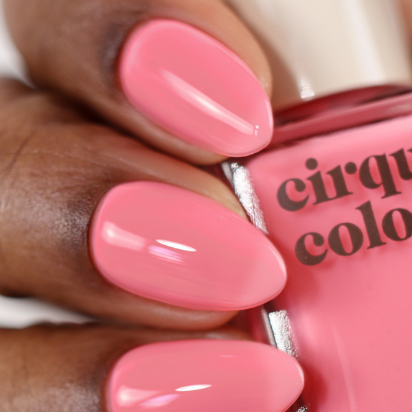 Close-up of pink nail polish on a hand with 'cirque color' bottle.