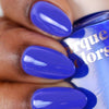 Hand with blue nail polish holding a bottle of blue nail polish.