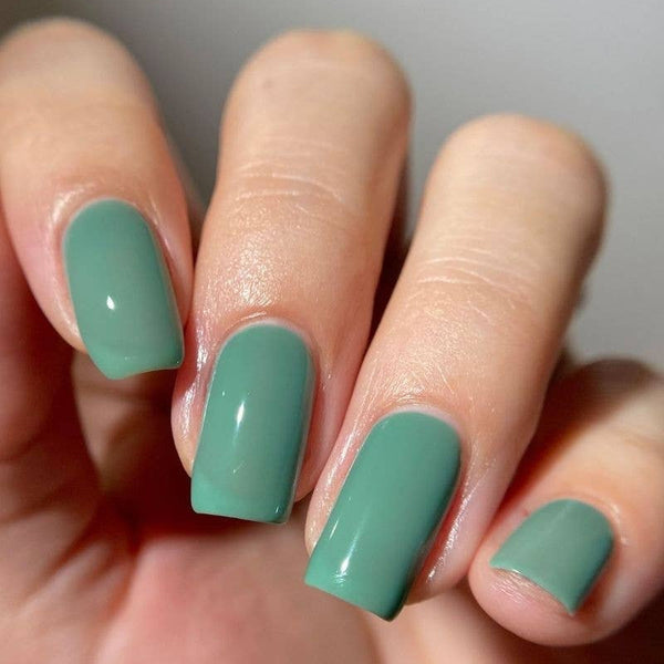 Close-up of hand with green nail polish.