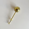 Gold toned stainless steel tea infuser on a neutral background.