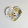 Heart-shaped ceramic dish with colorful abstract design on a light pink background