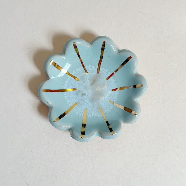 Decorative blue flower-shaped object with gold accents on a white background