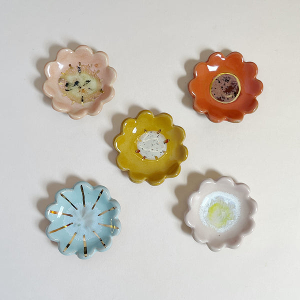 Set of five colorful mini ceramic flower-shaped dishes on a light gray background