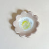 Pale pink floral-shaped dish with a yellow center on a white background