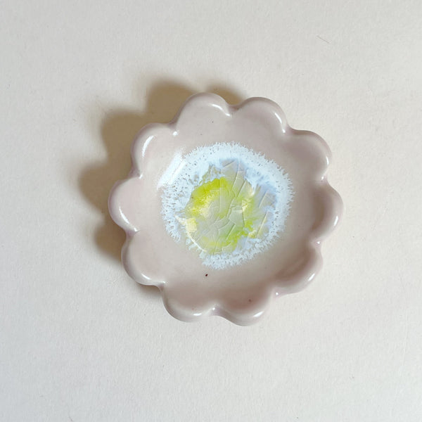 Pale pink floral-shaped dish with a yellow center on a white background