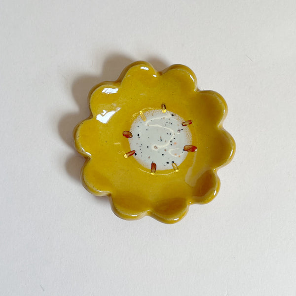 Yellow ceramic flower-shaped dish on a white background