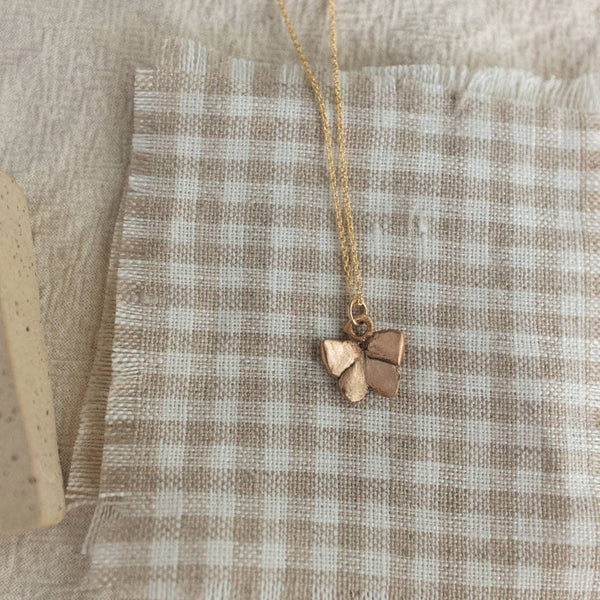 Butterfly pendant necklace on a checkered fabric background