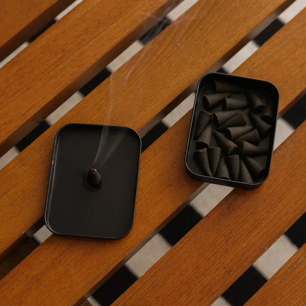 Black incense burner with smoke on a wooden surface