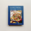 A dark blue cookbook called "Everything Delish" by Jamie Milne against a neutral background.