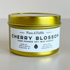 Gold candle tin with 'Cherry Blossom' label on a light background