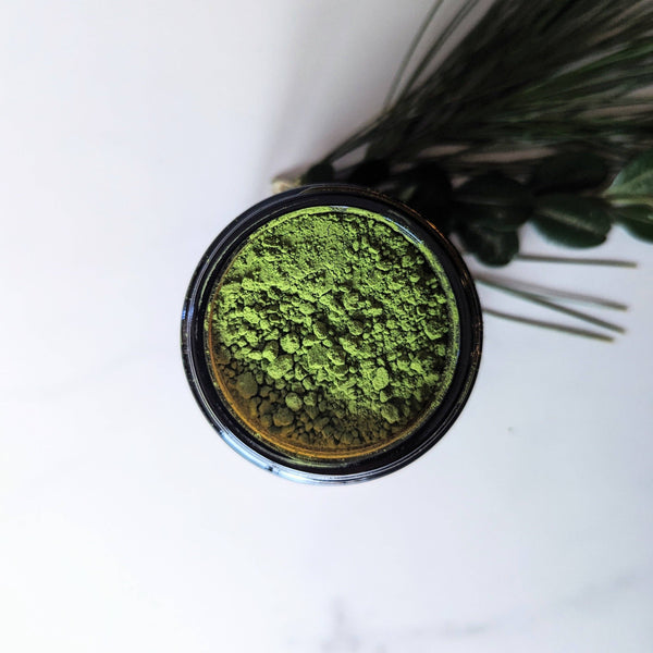 Top view of a container filled with green matcha powder on a white background