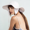 Woman wearing a white sun hat with a light background