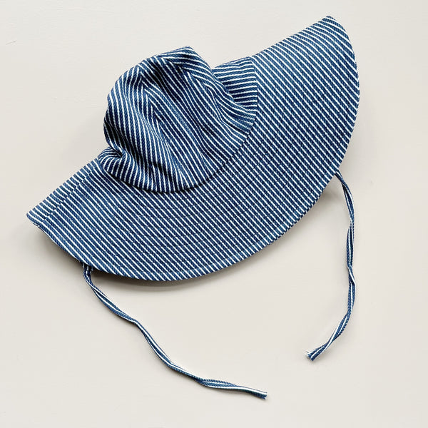 Blue and white striped sun hat on a light beige background