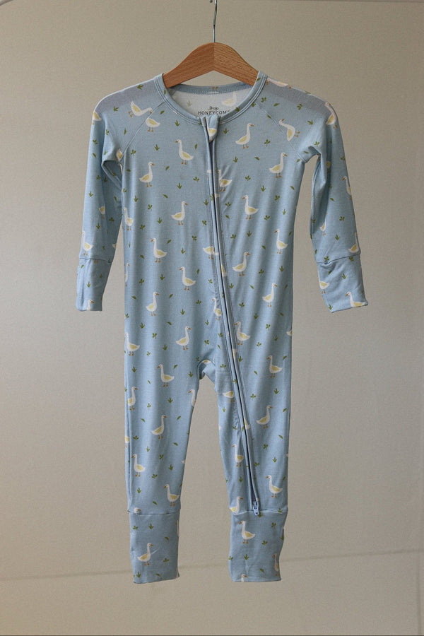 Blue baby onesie with geese pattern on a hanger against a beige wall.