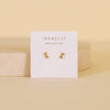 Gold earrings on a Jaxkelly branded card with a beige background