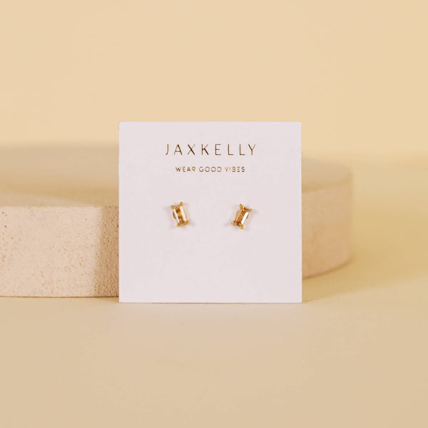 Gold earrings on a Jaxkelly branded card with a beige background