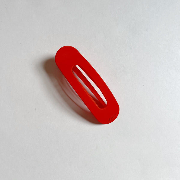 Bright red lay-flat hair claw on beige background.