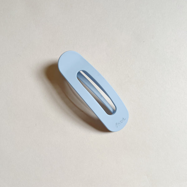 Pale blue lay-flat hair claw on beige background.