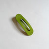 Bright green lay-flat hair claw on beige background.