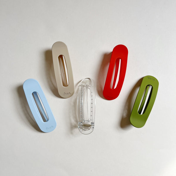 Assortment of oval shaped lay-flat hair claws on a beige background.