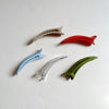 Side view of assorted lay-flat hair claws on beige background.