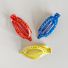 Three colorful hair clips (red, blue, yellow) with polka dot patterns on a light gray background.
