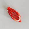 Red hair clip with white polka dots on a light gray background