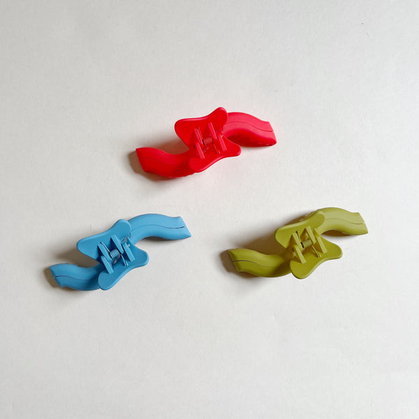 Three colorful wavy hair claws on a beige background.