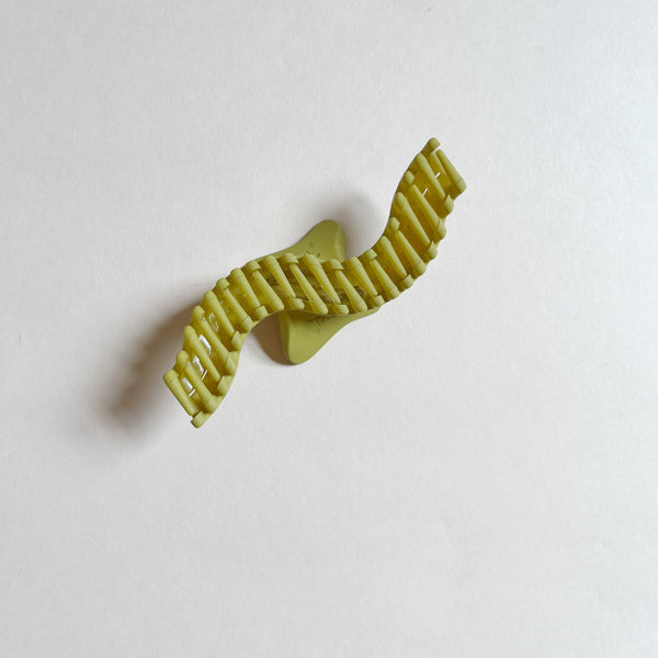 Wavy green hair claw on beige background.