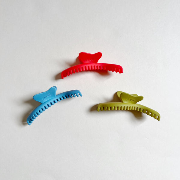 Three colorful wavy hair claws on beige background.
