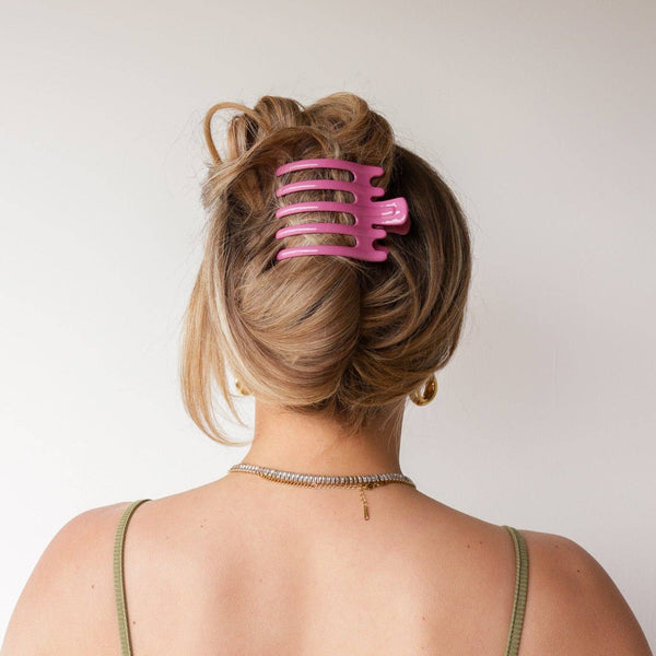 Person with a pink hair clip in their bun against a plain background
