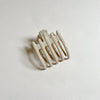 Shiny tan lay-flat hair claw on beige background.